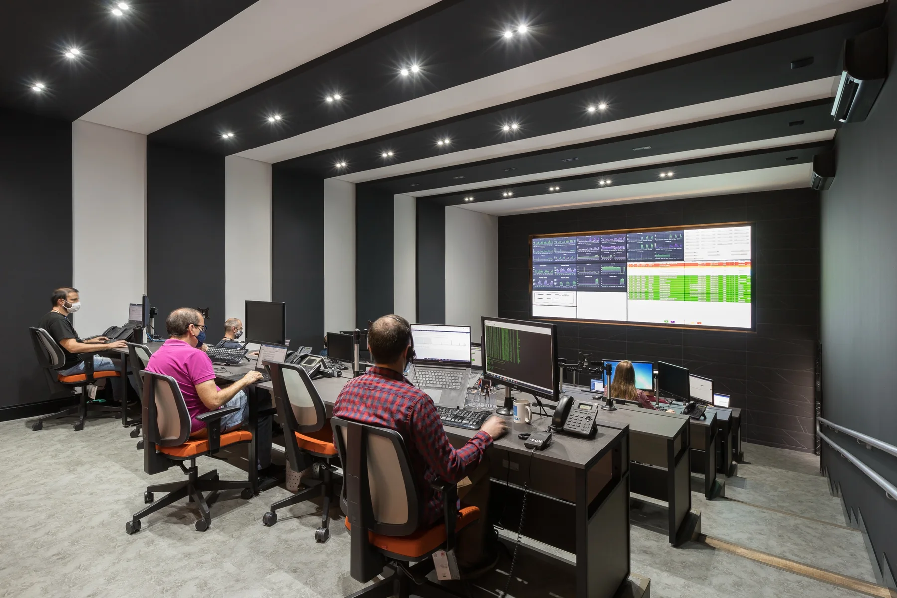 Sala do centro de operações de rede com operadores e painel de monitoramento